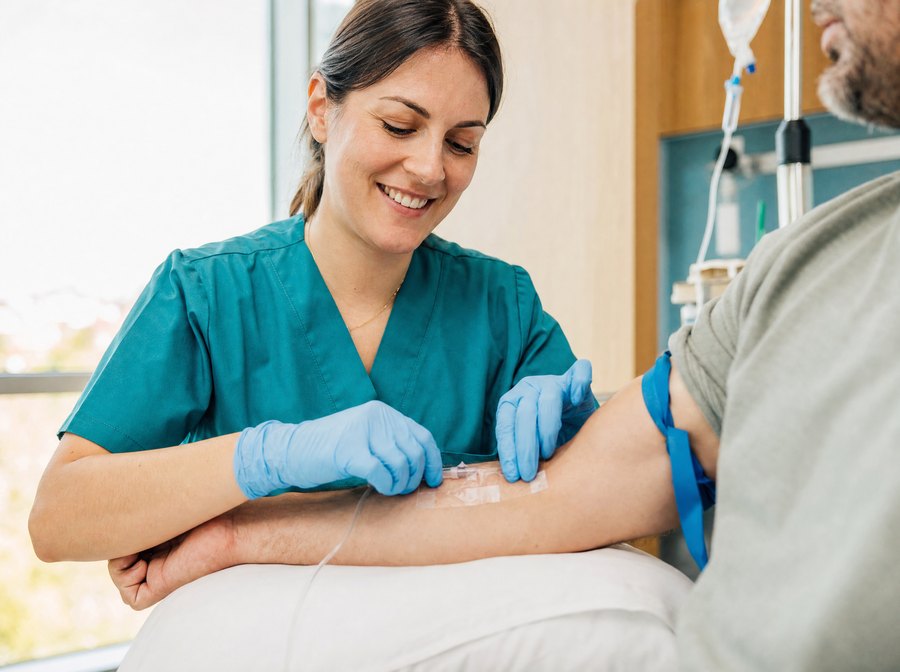 Nurse in scrubs securing a freshly placed IV line on a patient's forearm