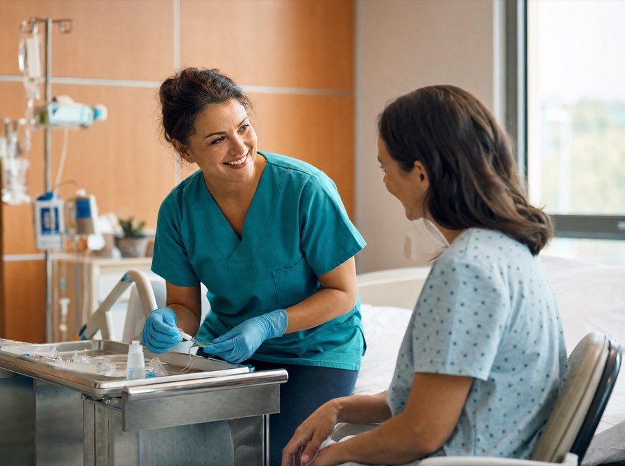 Nurse reassuring a seated patient while preparing for an IV